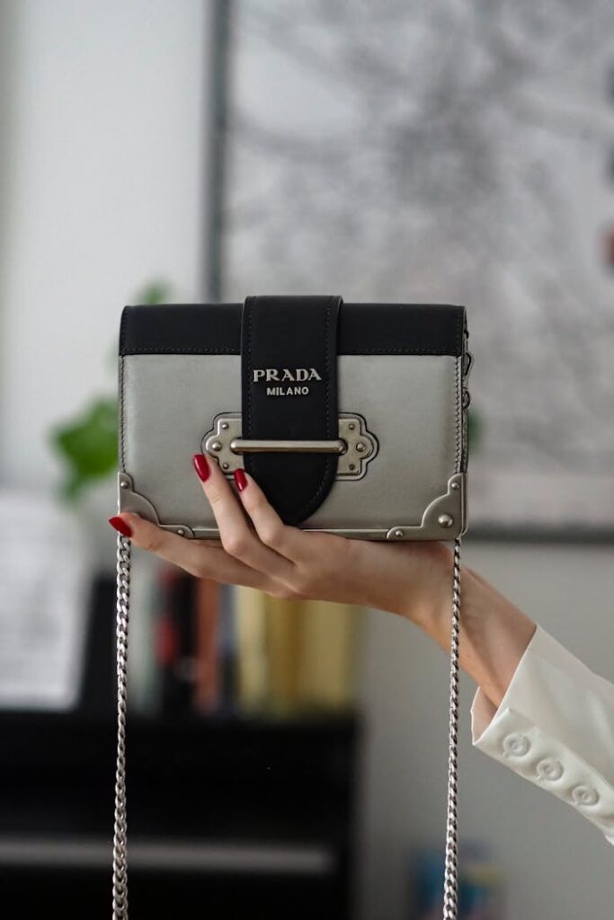 Stylish display of a Prada Milano handbag held in an elegantly manicured hand.